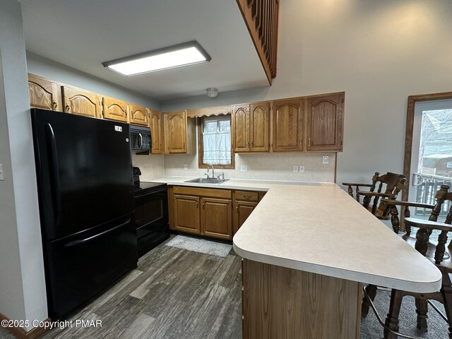 kitchen featuring dark wood-type flooring, kitchen peninsula, sink, and black appliances