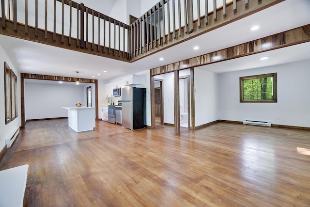 8210 Pine Grove Dr, East Stroudsburg, PA 18301 - unfurnished living room featuring a baseboard heating unit, a baseboard radiator, light wood-style floors, recessed lighting, and a towering ceiling