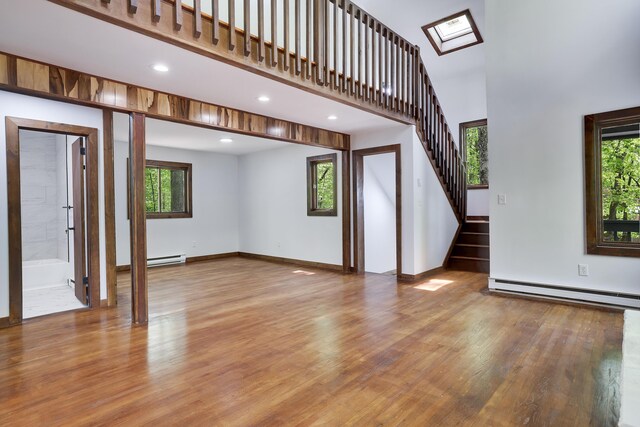 8210 Pine Grove Dr, East Stroudsburg, PA 18301 - unfurnished living room featuring a baseboard radiator, wood finished floors, a high ceiling, stairs, and baseboards