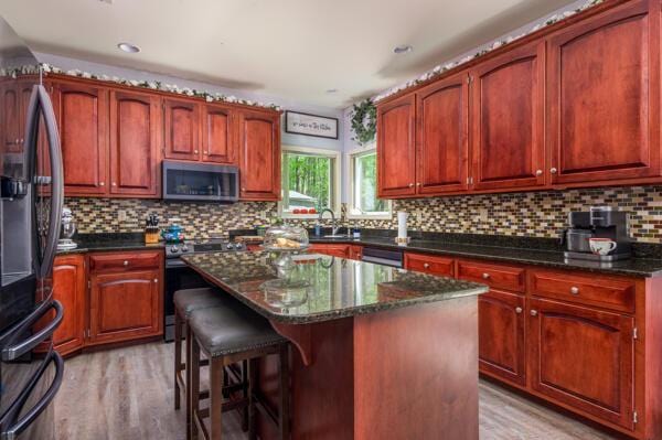 kitchen featuring appliances with stainless steel finishes, light wood finished floors, backsplash, a kitchen island, and recessed lighting