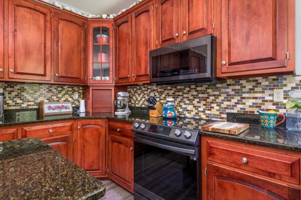 kitchen with stainless steel electric range oven, dark stone counters, and tasteful backsplash