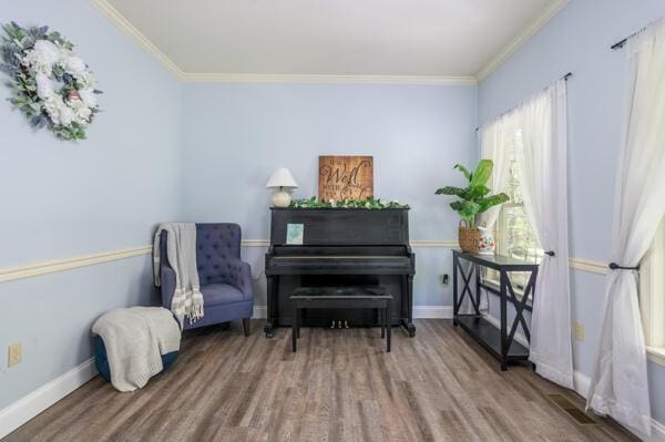 sitting room with wood finished floors, ornamental molding, and baseboards