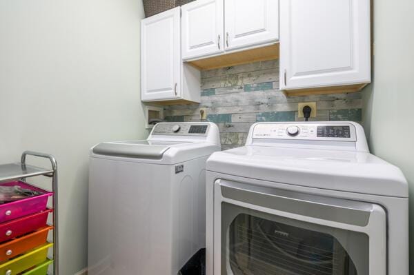 laundry room with washer and clothes dryer, cabinet space, and wood walls