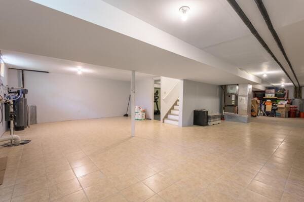 finished basement featuring stairs and water heater