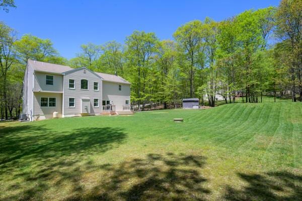 rear view of property with a lawn, an outbuilding, and a storage shed