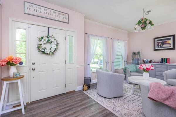 living room with wood finished floors, healthy amount of natural light, crown molding, and baseboards