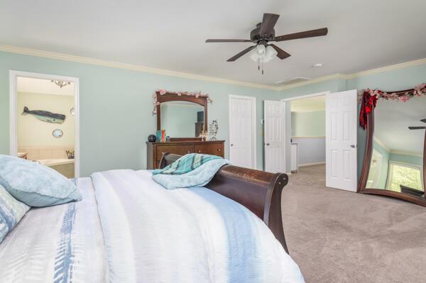 bedroom with crown molding, carpet floors, ensuite bath, ceiling fan, and baseboards