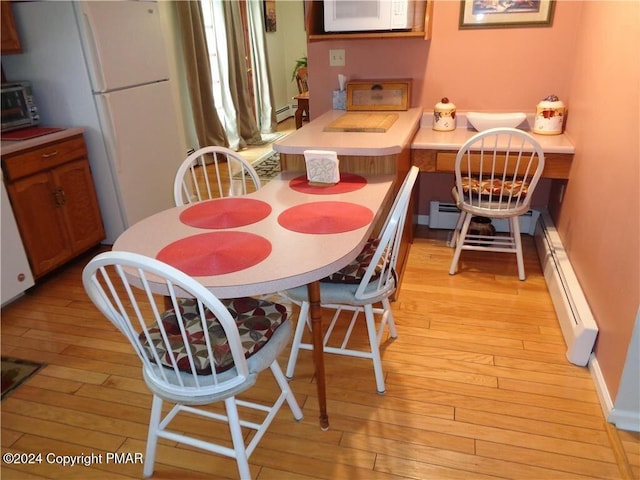 dining room with light wood-type flooring, a toaster, and a baseboard heating unit