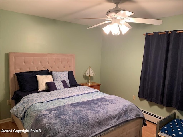 bedroom featuring light wood-style floors, baseboard heating, and a ceiling fan