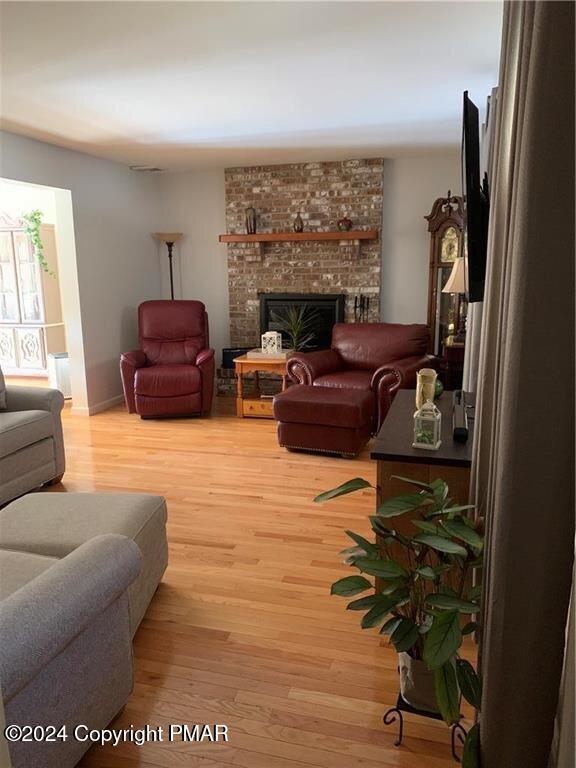 living area with light wood finished floors and a brick fireplace