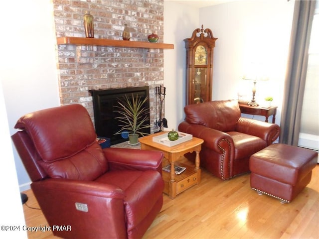 living area with a brick fireplace and wood finished floors