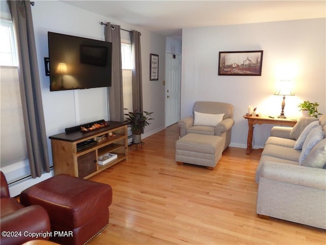 living area with a wealth of natural light, baseboards, baseboard heating, and light wood finished floors