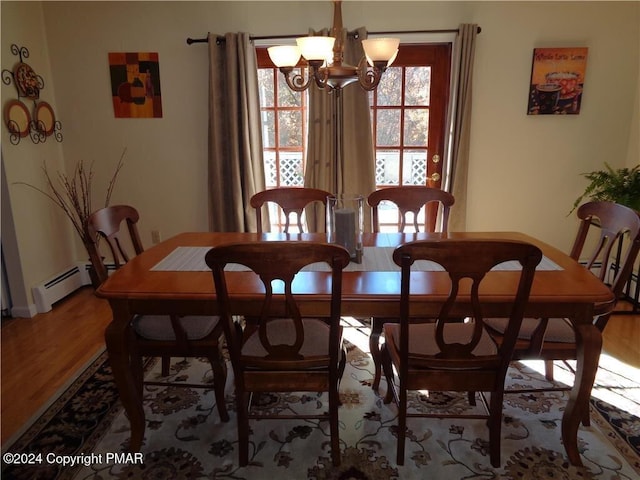 dining room with a baseboard heating unit, a notable chandelier, baseboards, and wood finished floors