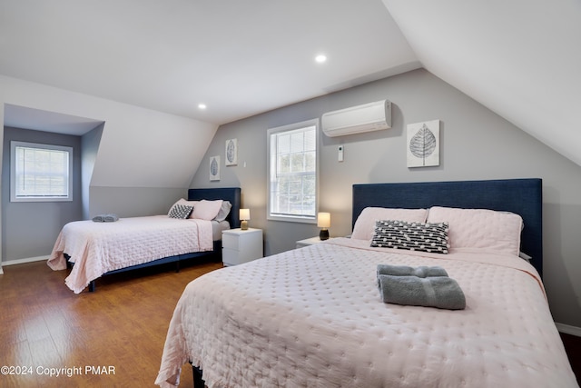 bedroom with vaulted ceiling, a wall unit AC, wood finished floors, and baseboards