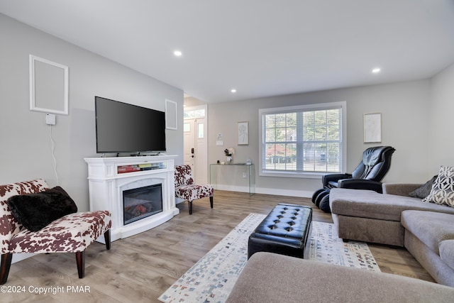 living room featuring a premium fireplace, baseboards, wood finished floors, and recessed lighting