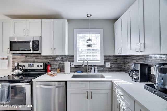 kitchen featuring appliances with stainless steel finishes, light countertops, white cabinets, and a sink