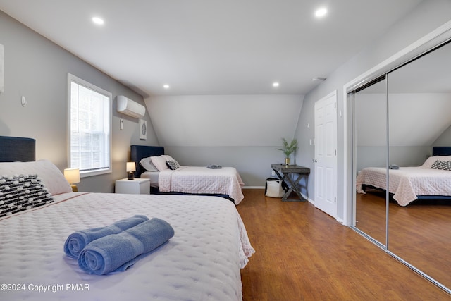 bedroom featuring a closet, vaulted ceiling, wood finished floors, and an AC wall unit