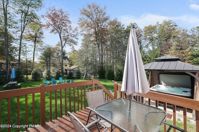 deck featuring outdoor dining space, a covered hot tub, a yard, and a gazebo