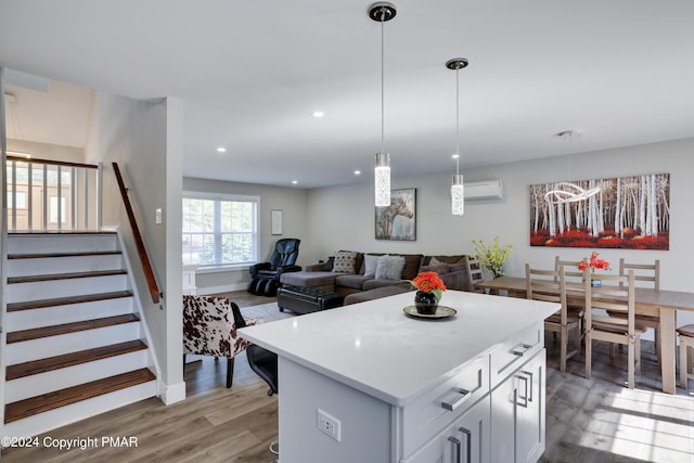 kitchen featuring a wall unit AC, recessed lighting, light countertops, light wood finished floors, and decorative light fixtures