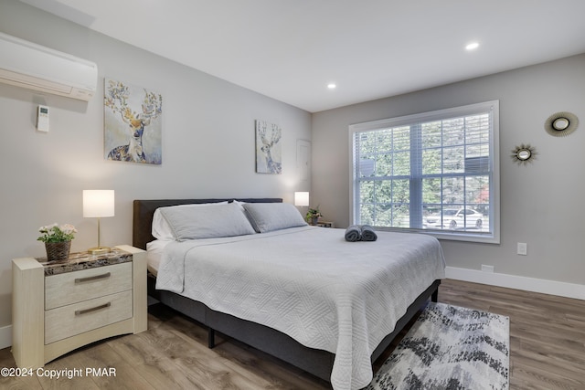 bedroom with recessed lighting, a wall mounted air conditioner, wood finished floors, and baseboards