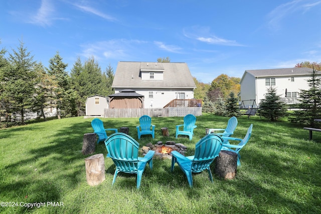 view of yard with an outdoor fire pit, an outdoor structure, fence, a wooden deck, and a storage unit