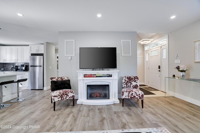 living room featuring baseboards, a premium fireplace, light wood-style flooring, and recessed lighting