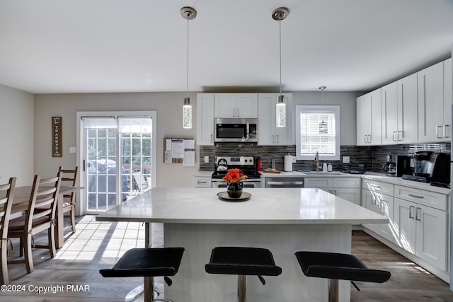 kitchen with appliances with stainless steel finishes, a sink, a kitchen bar, and tasteful backsplash