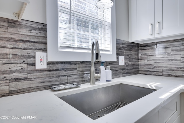 room details featuring tasteful backsplash, white cabinetry, and a sink