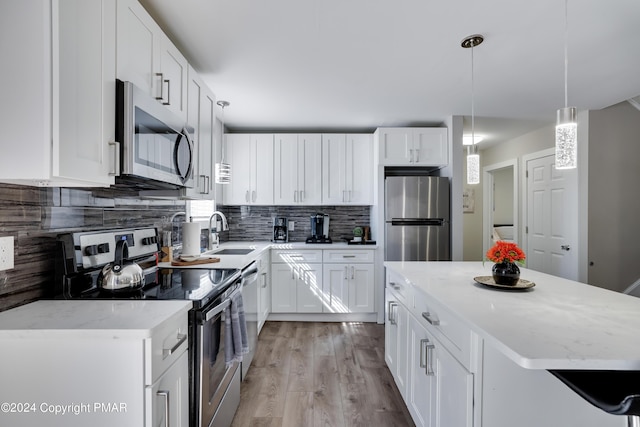 kitchen featuring stainless steel appliances, backsplash, white cabinetry, a sink, and a kitchen island