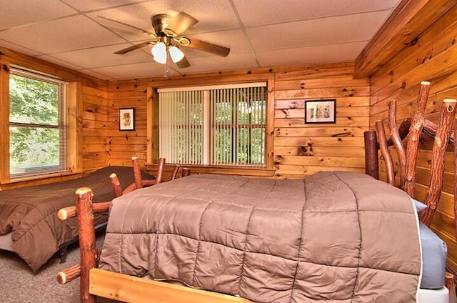 carpeted bedroom with wood walls and ceiling fan