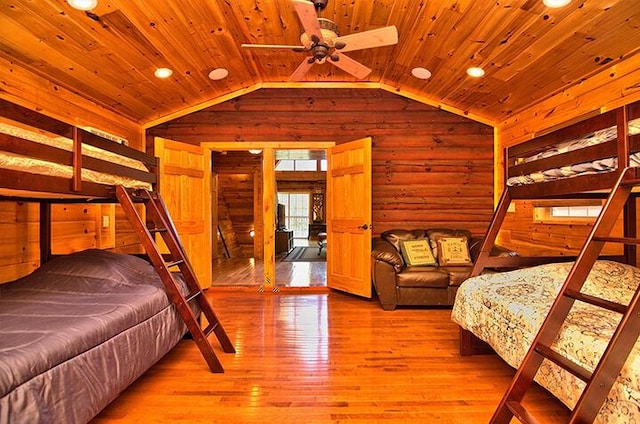 bedroom with wood walls, wood ceiling, vaulted ceiling, and wood finished floors