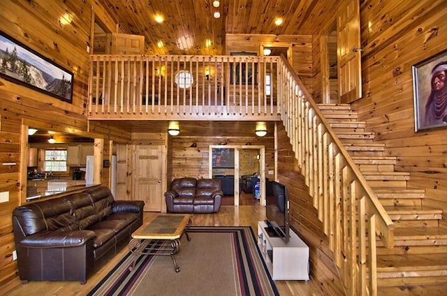 living room with wood ceiling, wooden walls, a high ceiling, and stairs