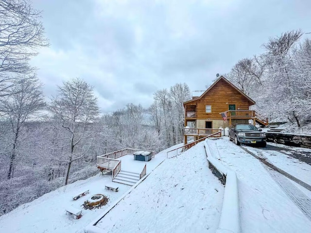 view of snow covered exterior with stairway, a deck, and a view of trees