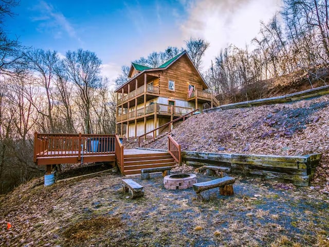 back of house with a fire pit, a balcony, and a wooden deck