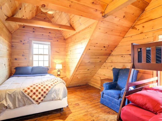 bedroom with lofted ceiling with beams, wood walls, and hardwood / wood-style flooring