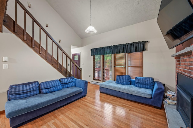 1117 Belaire Dr, East Stroudsburg, PA 18301 - living area with stairs, a brick fireplace, wood-type flooring, high vaulted ceiling, and a textured ceiling