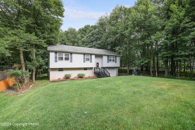 bi-level home with a garage, a front yard, and fence