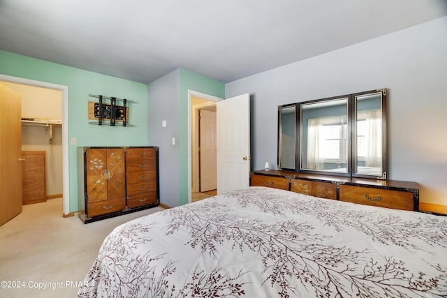 bedroom with carpet flooring, a spacious closet, and baseboards