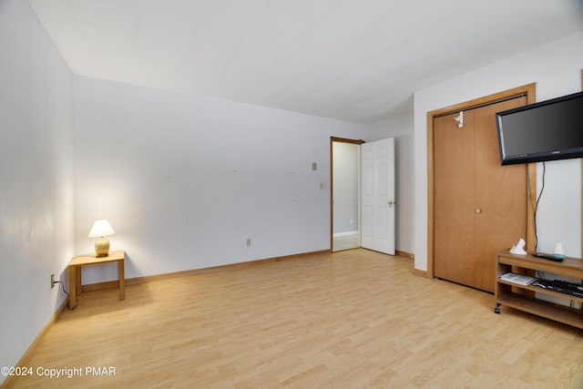 unfurnished bedroom featuring light wood-style flooring, baseboards, and a closet