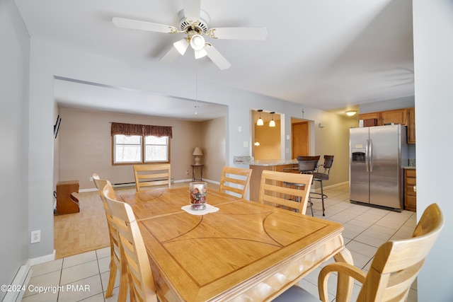 dining space with light tile patterned flooring, a ceiling fan, and baseboards