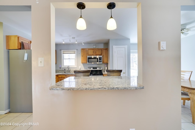 kitchen featuring a peninsula, light tile patterned floors, stainless steel appliances, and a sink