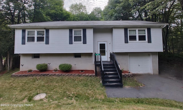 split foyer home featuring a garage, a front yard, and stucco siding