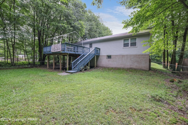 rear view of house with fence, stairway, a deck, and a yard