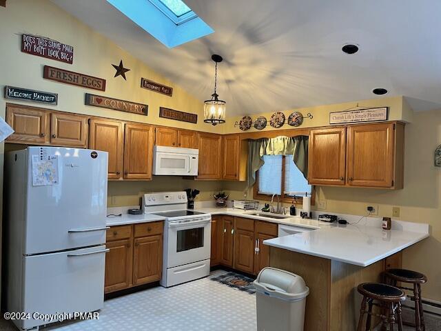 kitchen with white appliances, brown cabinetry, a peninsula, and a sink