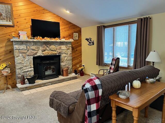 living area with wooden walls, carpet flooring, and vaulted ceiling