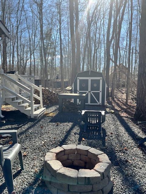 view of yard featuring an outbuilding, a fire pit, and a shed