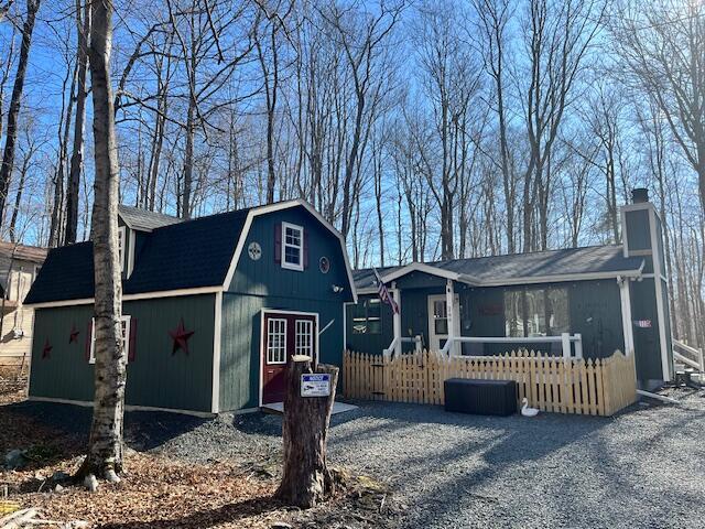 view of front of home with an outbuilding, a gambrel roof, a chimney, and fence