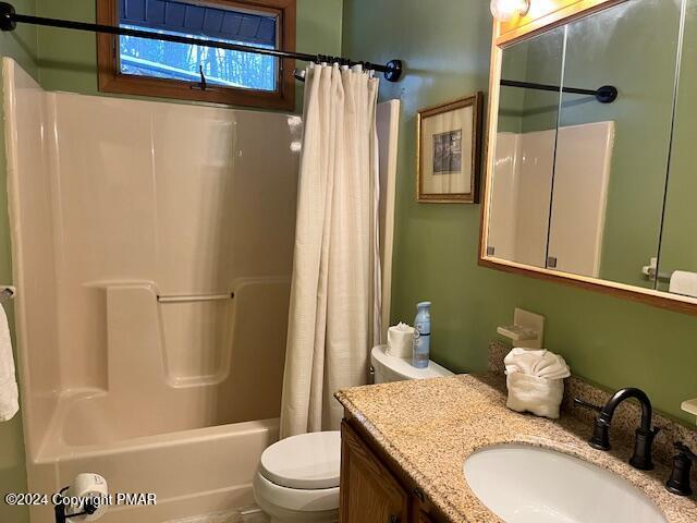 full bathroom featuring shower / bath combo with shower curtain, toilet, and vanity