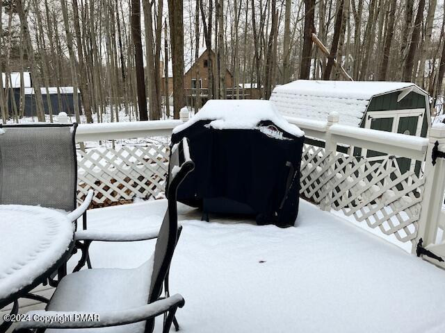 snow covered deck with a shed and an outdoor structure