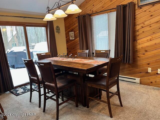 dining room featuring wooden walls, light colored carpet, and baseboard heating